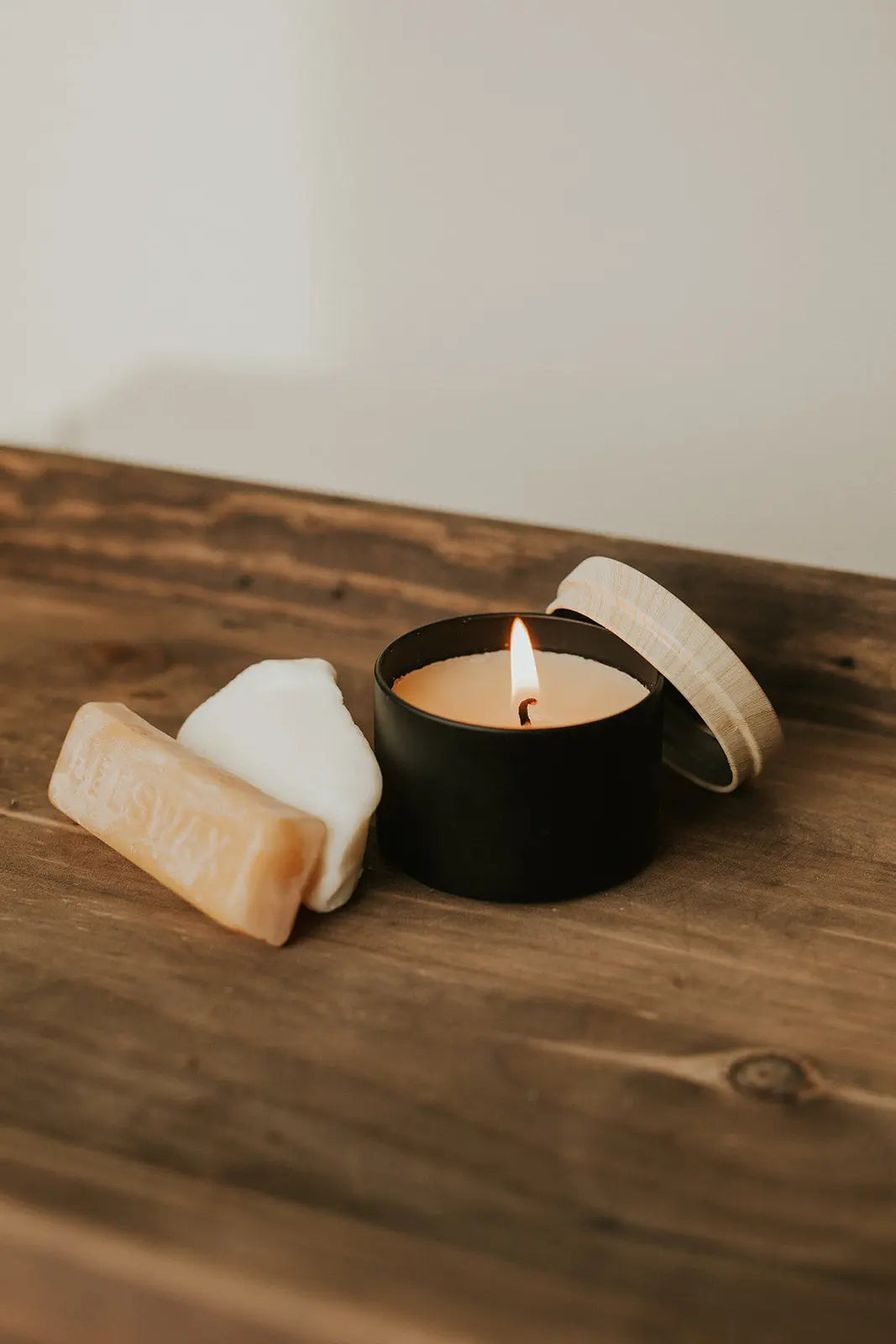 Candle and soap on a wooden surface with a neutral background