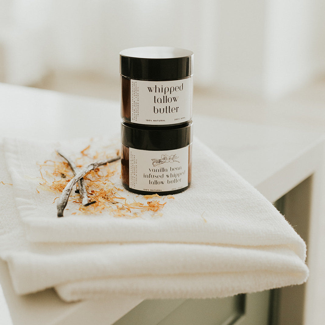 Two jars of whipped butter on a white surface with a blurred background