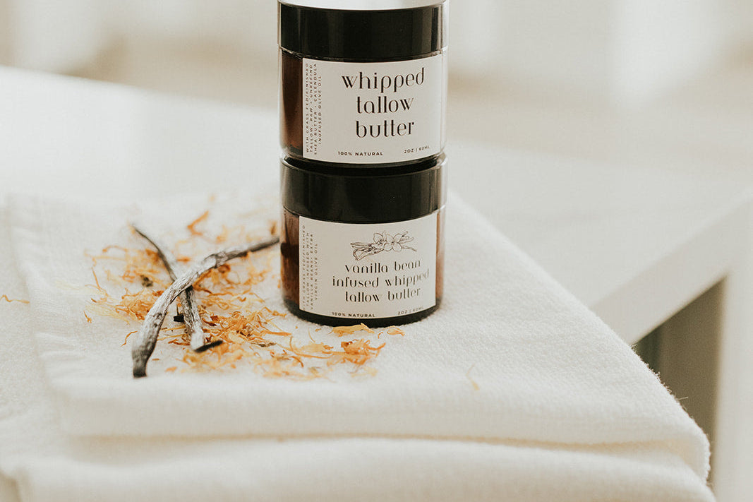 Two jars of whipped butter on a white surface with a blurred background