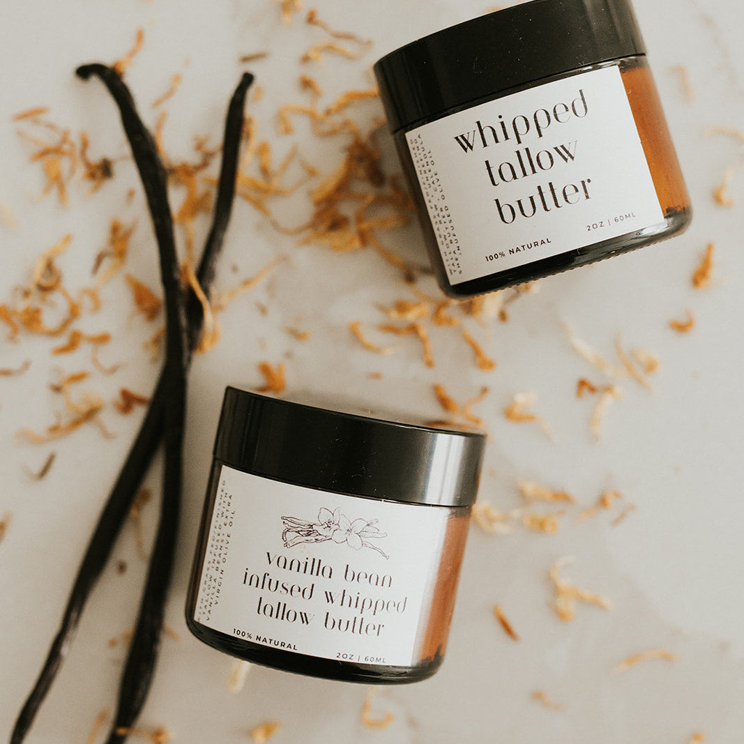 Two jars of 'whipped lallow butter' with vanilla beans on a light background