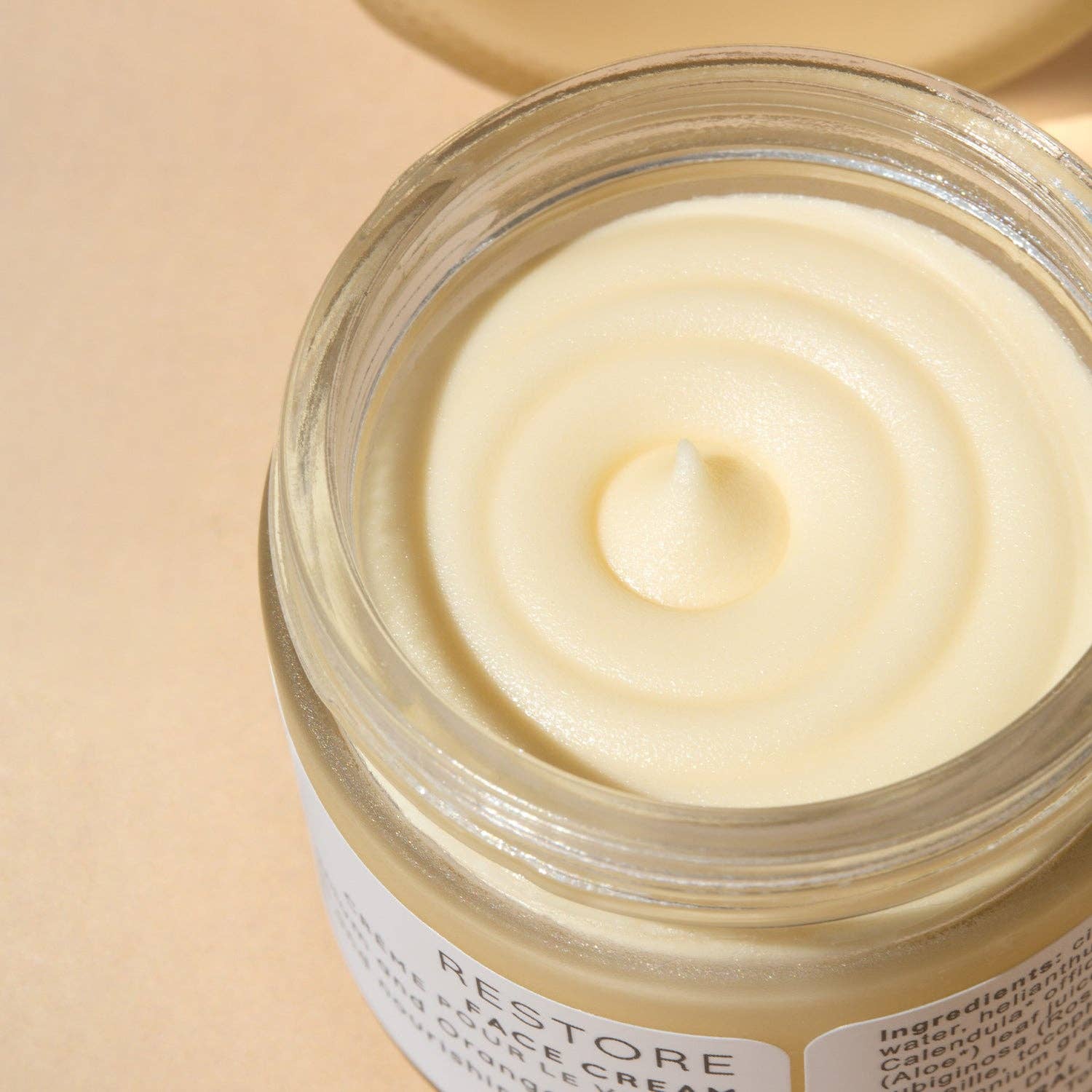 Jar of face cream with a visible brand name on a beige background