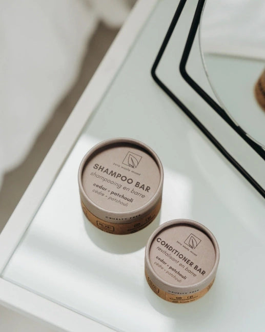 Cedar and patchouli conditioner bar zero waste Two eco-friendly shampoo and conditioner bars in brown containers on a white surface.