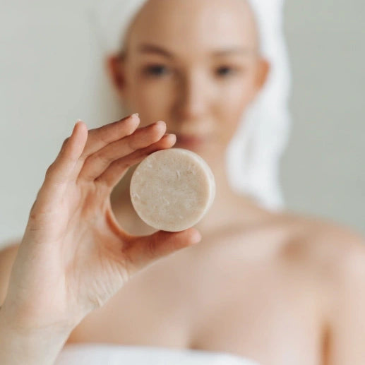Person holding a bar of soap with a blurred background Cedar and patchouli conditioner bar zero waste