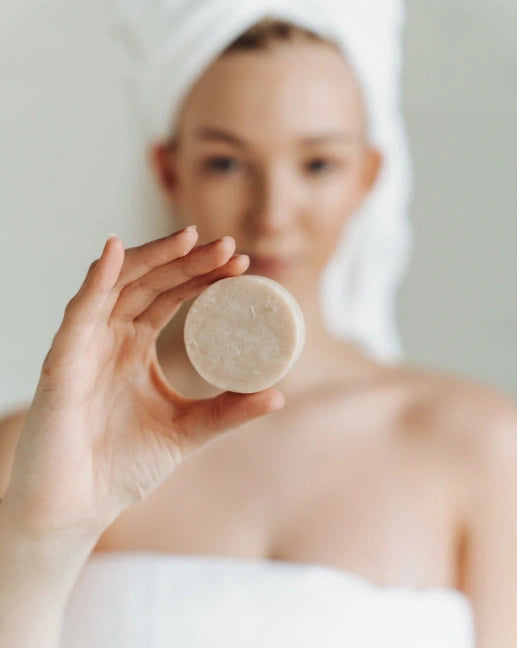 Person holding a bar of soap with a blurred background Cedar and patchouli conditioner bar zero waste