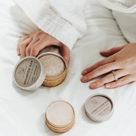 Person holding a container of shampoo bar with other bars on a white surface