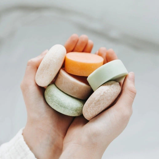 Hand holding a stack of colorful soap bars against a neutral background Eco-friendly conditioner bar made in Canada