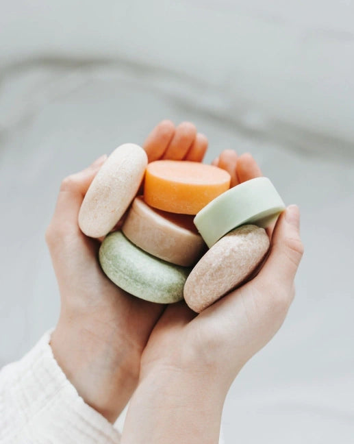 Hand holding a stack of colorful soap bars against a neutral background Eco-friendly conditioner bar made in Canada