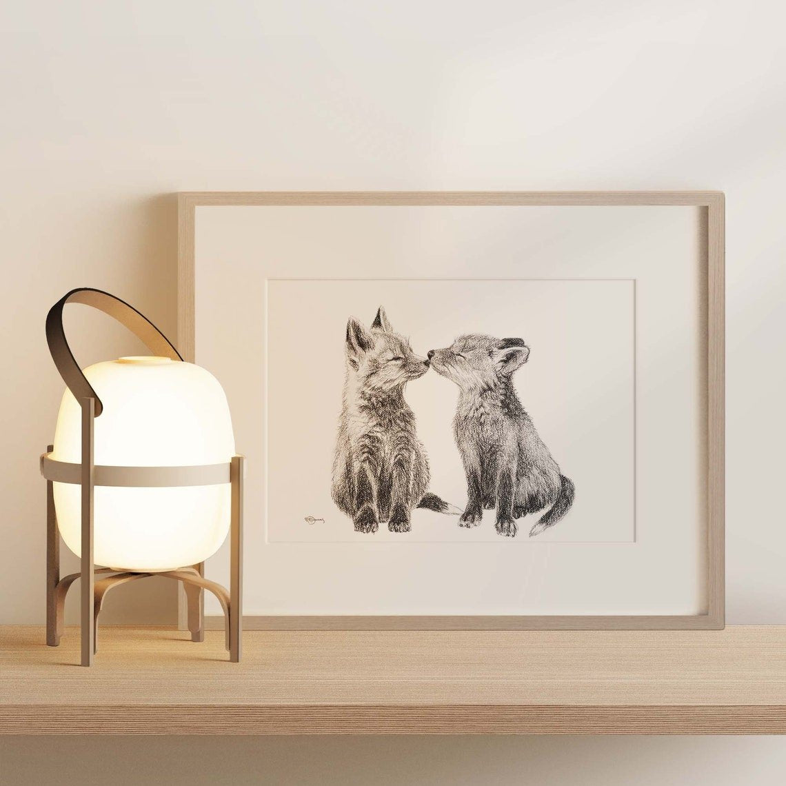 Framed artwork of two animals kissing on a wooden shelf with a lamp.