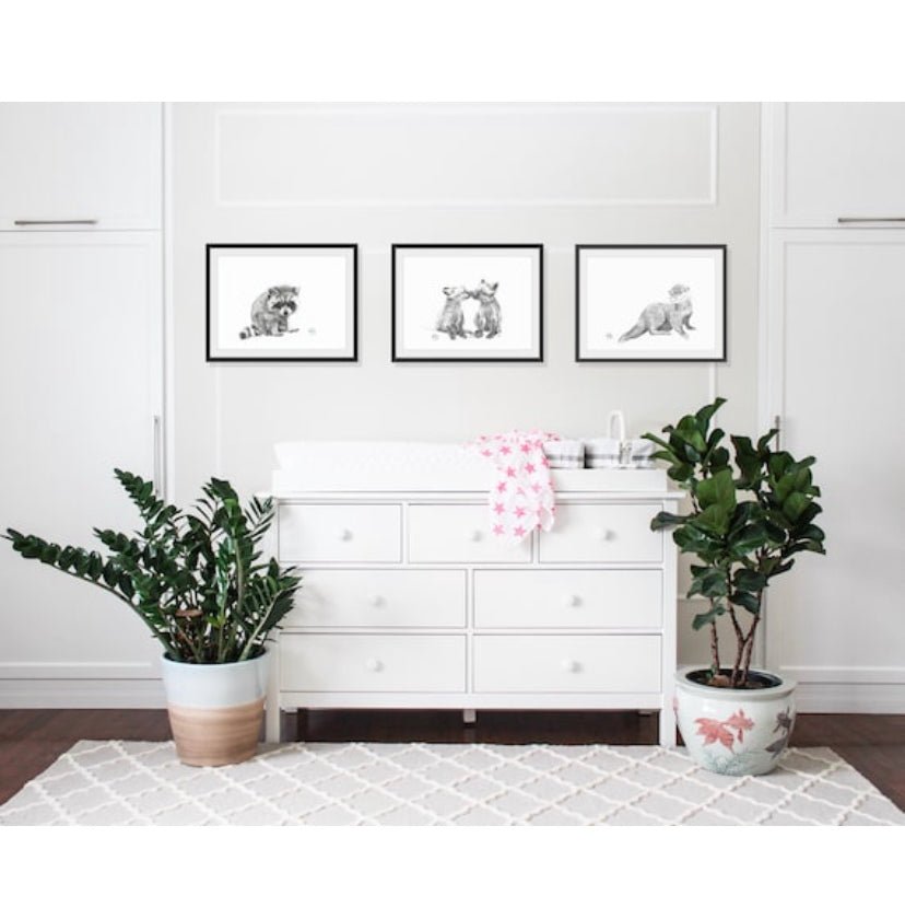 White dresser with decorative items and framed pictures in a room with plants.