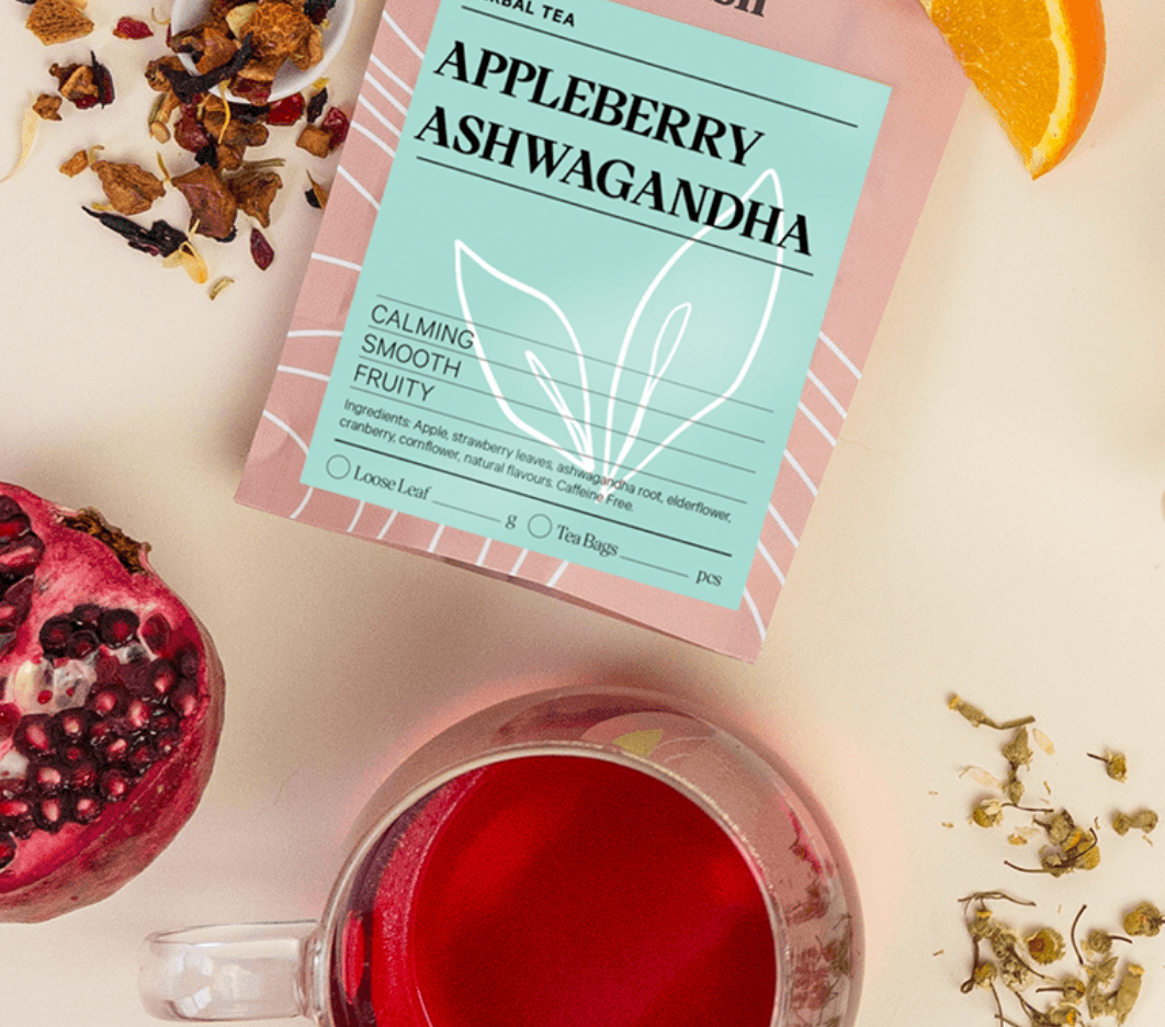 Tea package labeled 'Appleberry Ashwagandha' with a cup of tea, pomegranate, and orange on a light background.