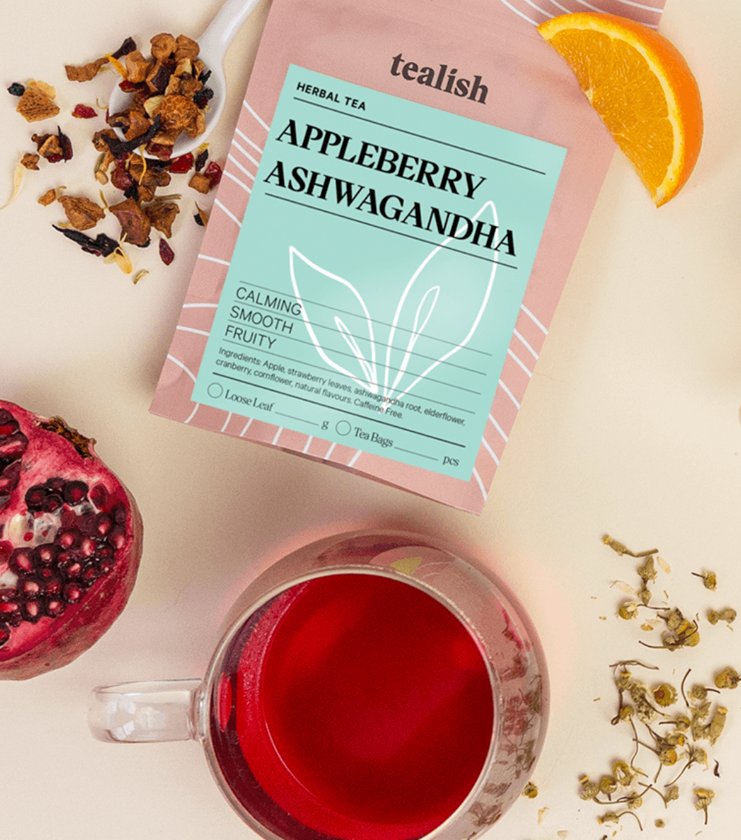 Tea package labeled 'Appleberry Ashwagandha' with a cup of tea, pomegranate, and orange on a light background.