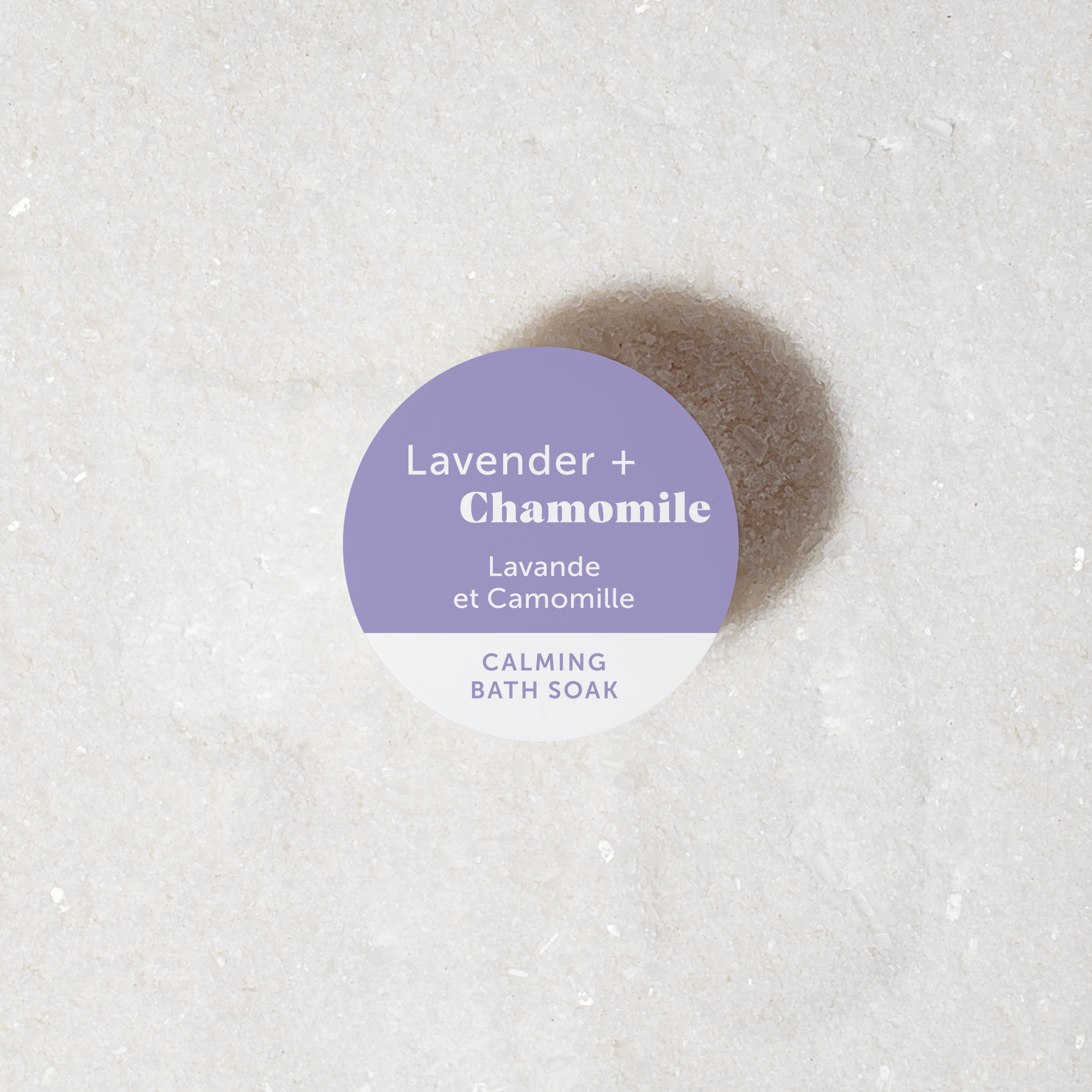 Bath soak powder labeled 'Lavender + Chamomile' on a textured white surface