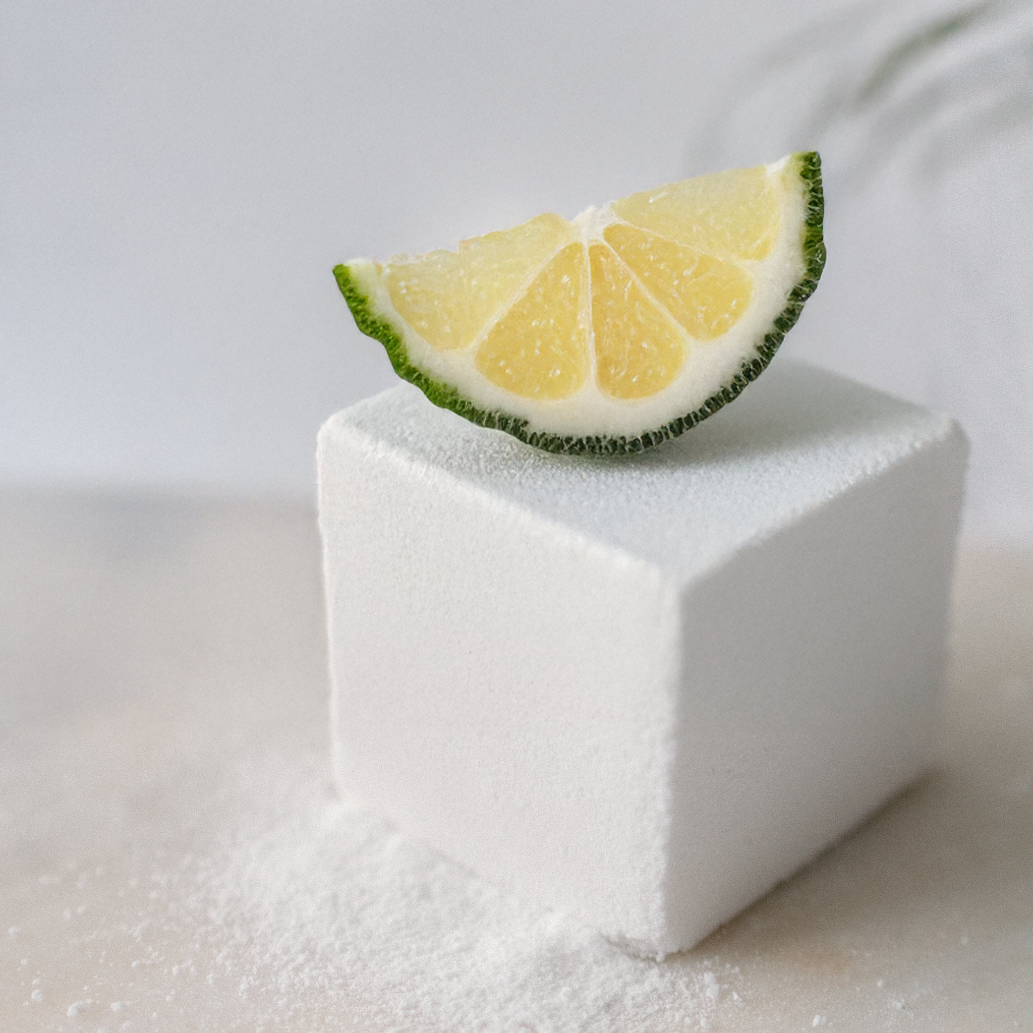 Block of sugar with a slice of lemon on top against a white background