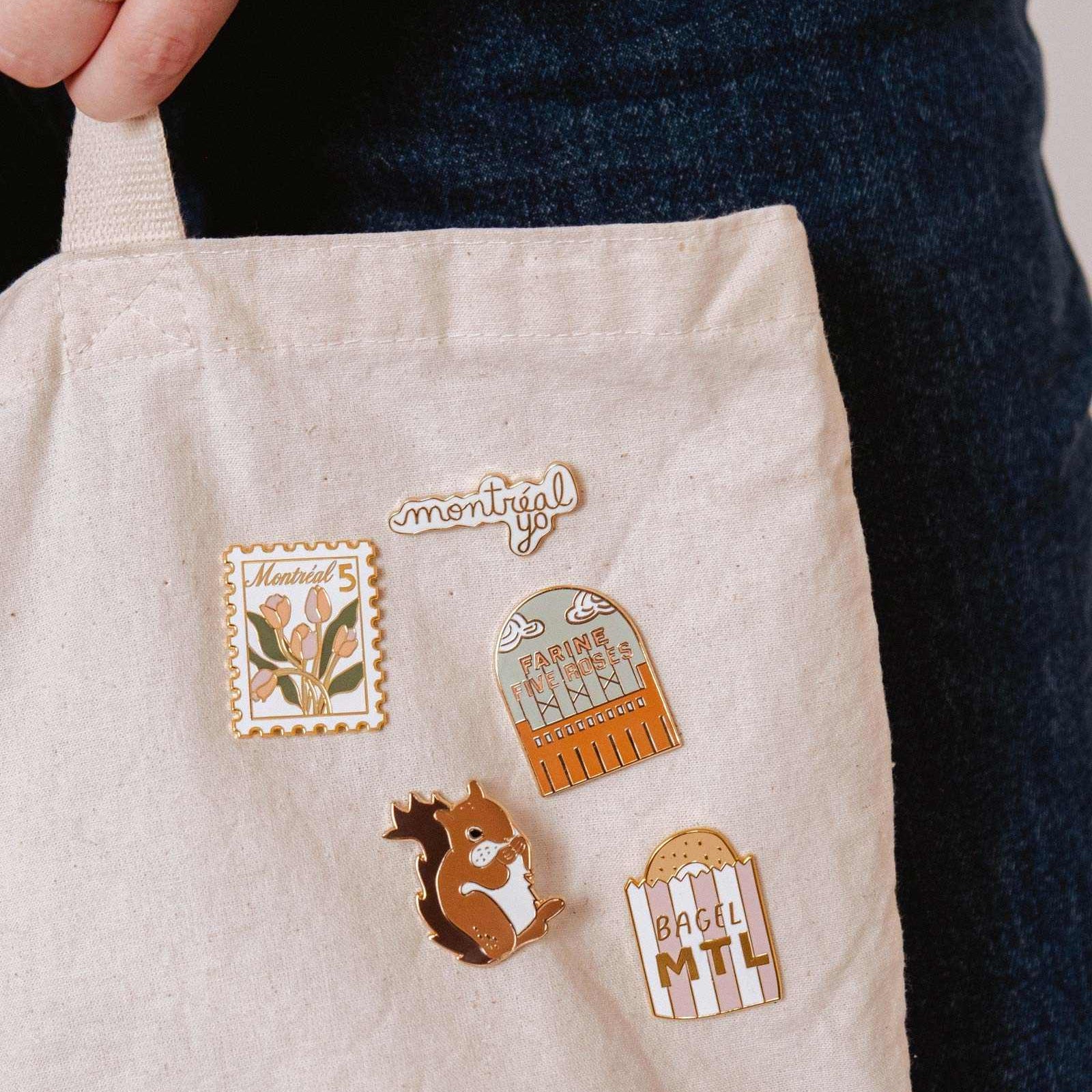mimi-and-august Beige fabric with nature-themed pins and 'montreal' text, held by a person wearing a dark jacket.