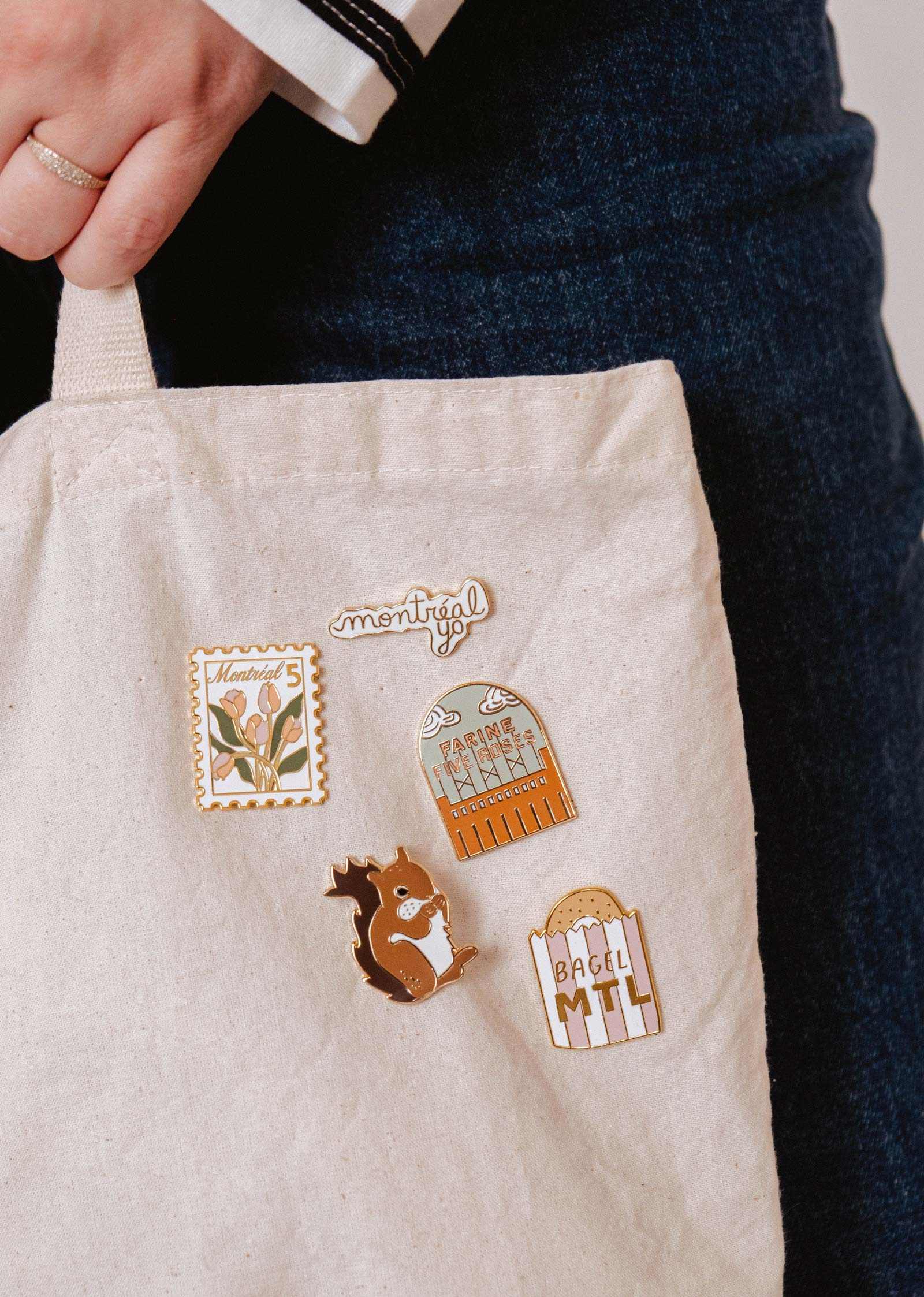 mimi-and-august Beige fabric with nature-themed pins and 'montreal' text, held by a person wearing a dark jacket.