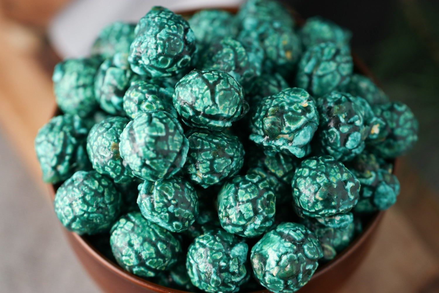 Close view of a Bowl of blue raspberry candied popcorn on a wooden surface from Toronto Popcorn company
