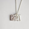 Silver necklace with 'BRAT' pendant on a light gray background