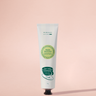Hand cream tube with green label on a pink background