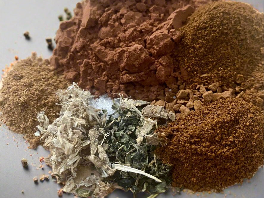 Spices including ground brown, red, and green on a gray background