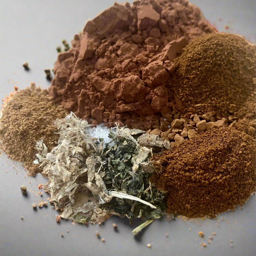 Spices including ground brown, red, and green on a gray background