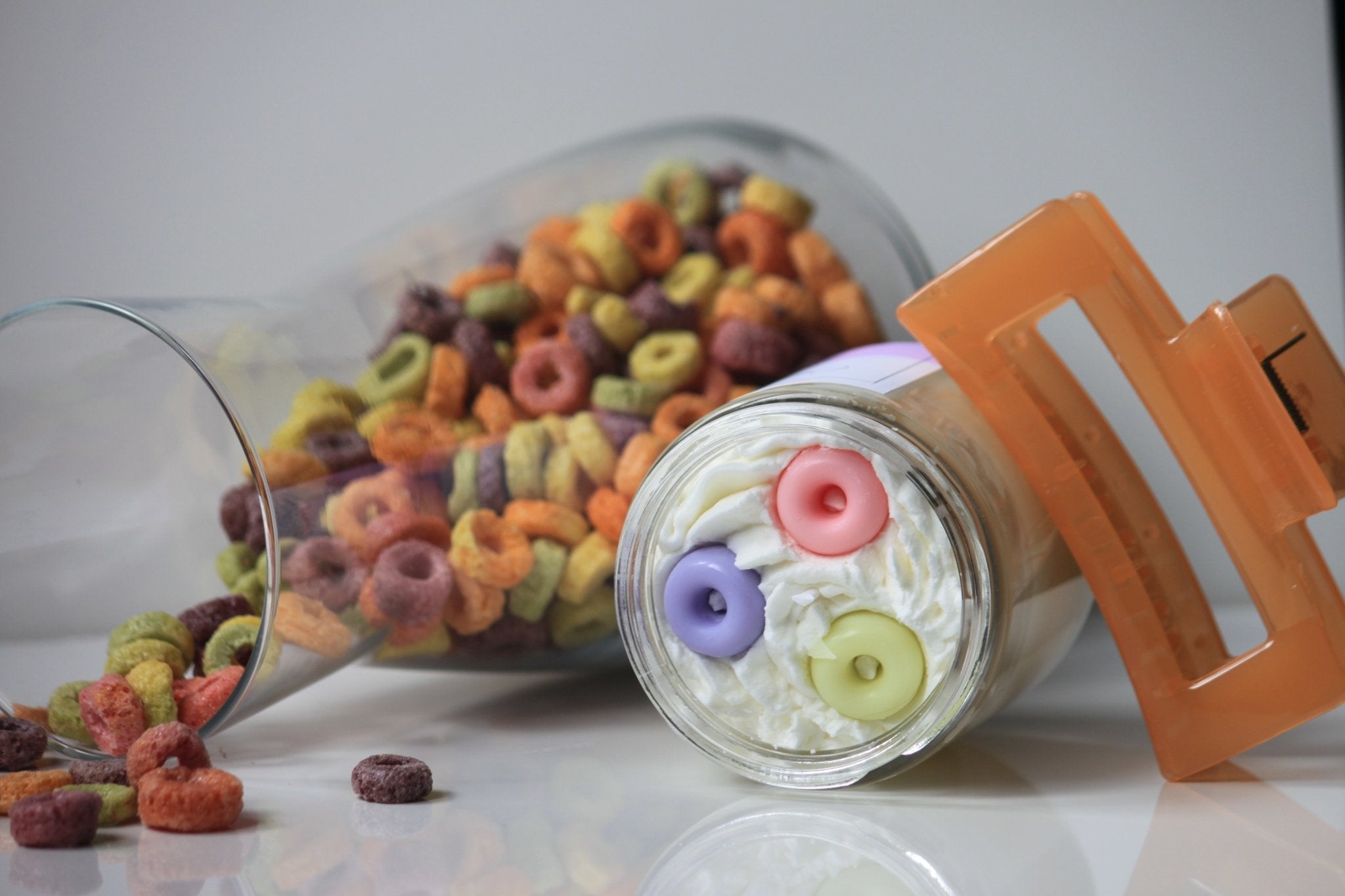 Colorful cereal spills out of a glass jar onto a white surface.