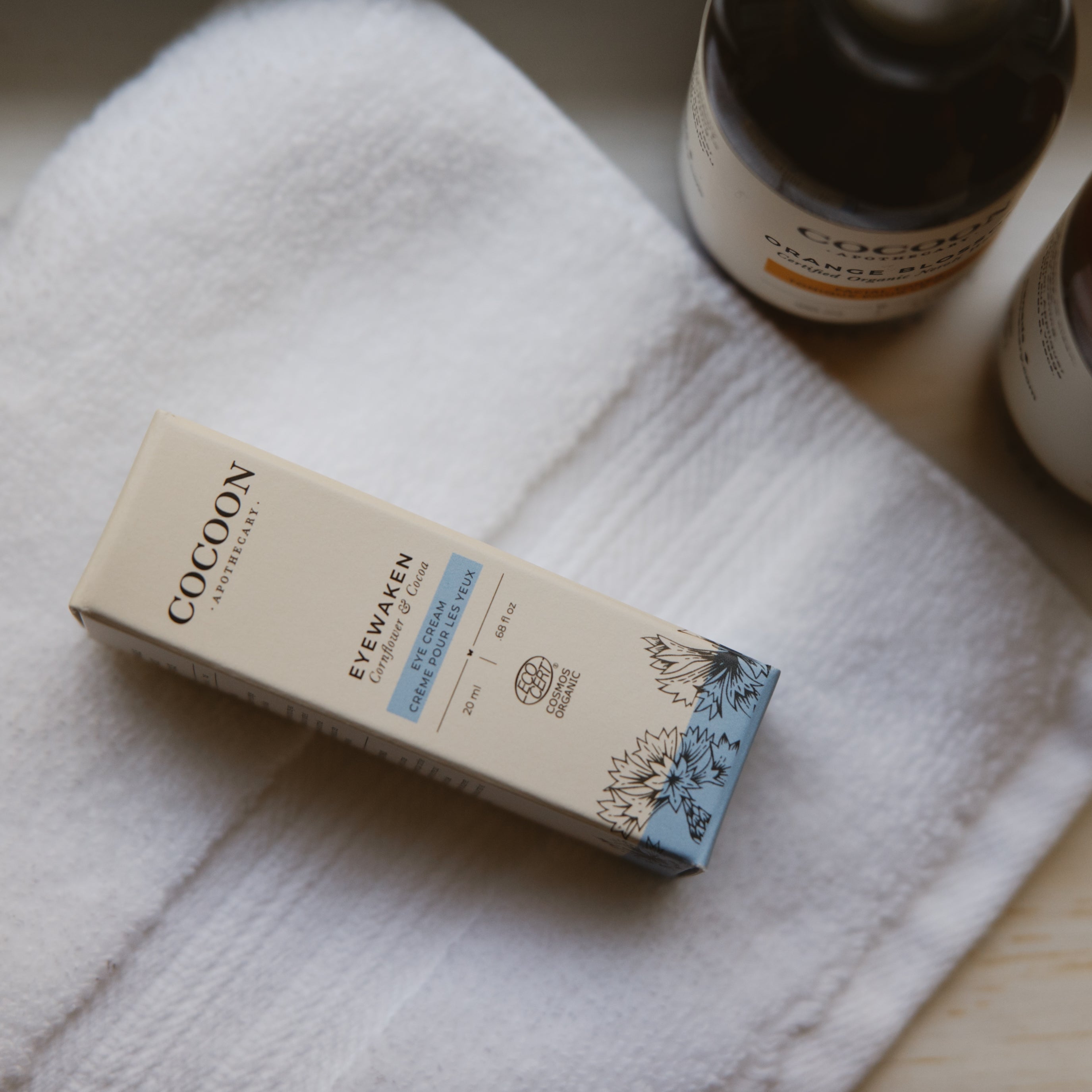 Cocoon skincare product box on a white towel with a bottle in the background