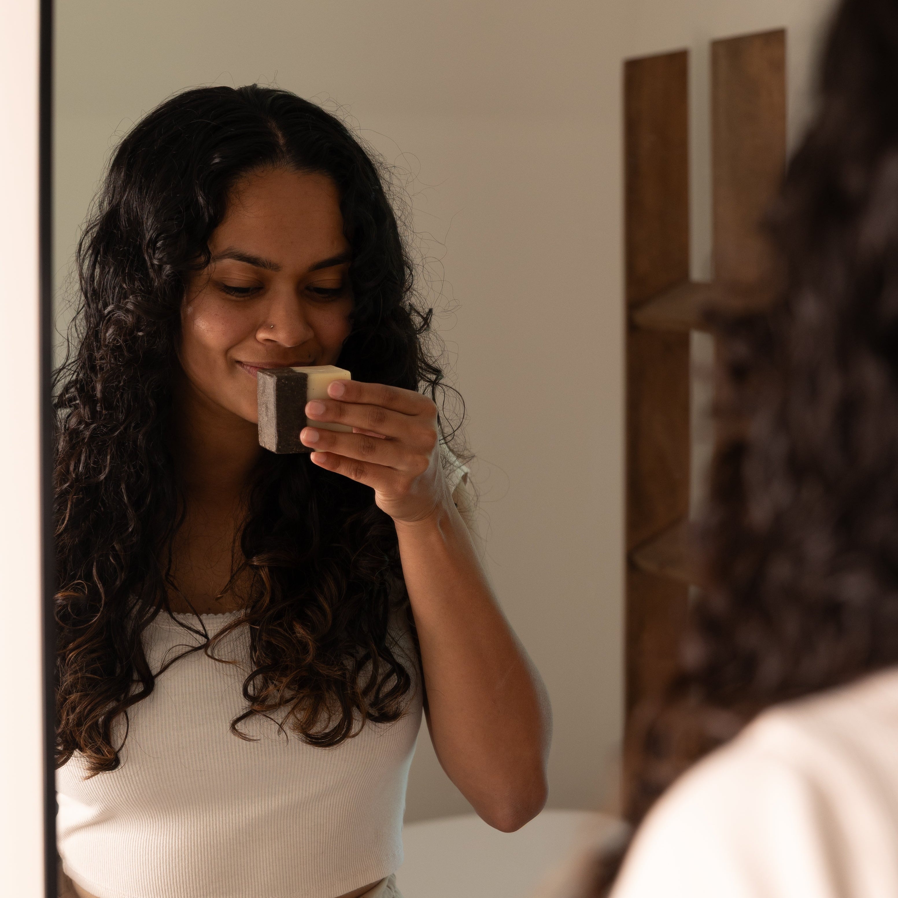 Woman applying cream to her face in front of a mirror