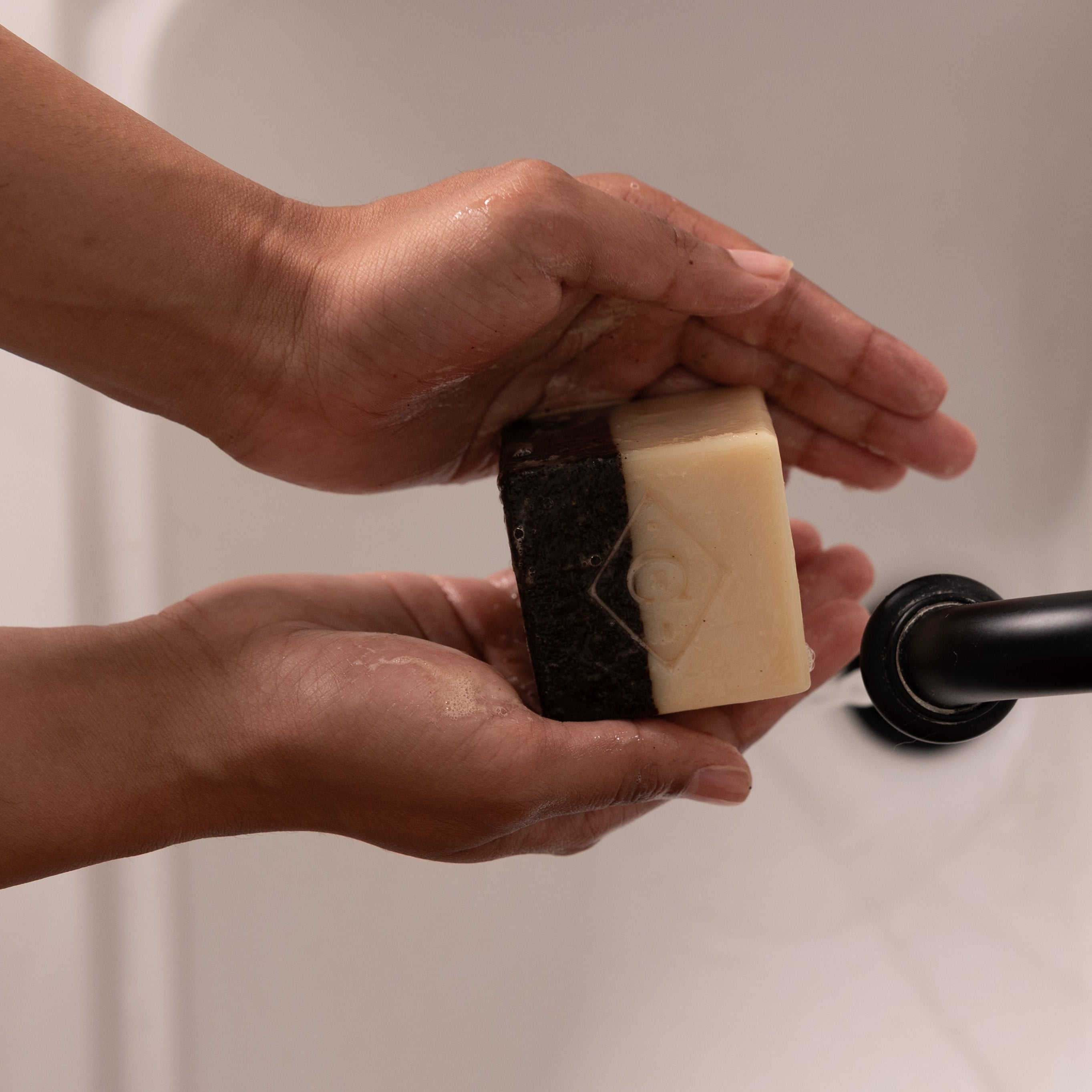 Person holding a bar of soap over a sink