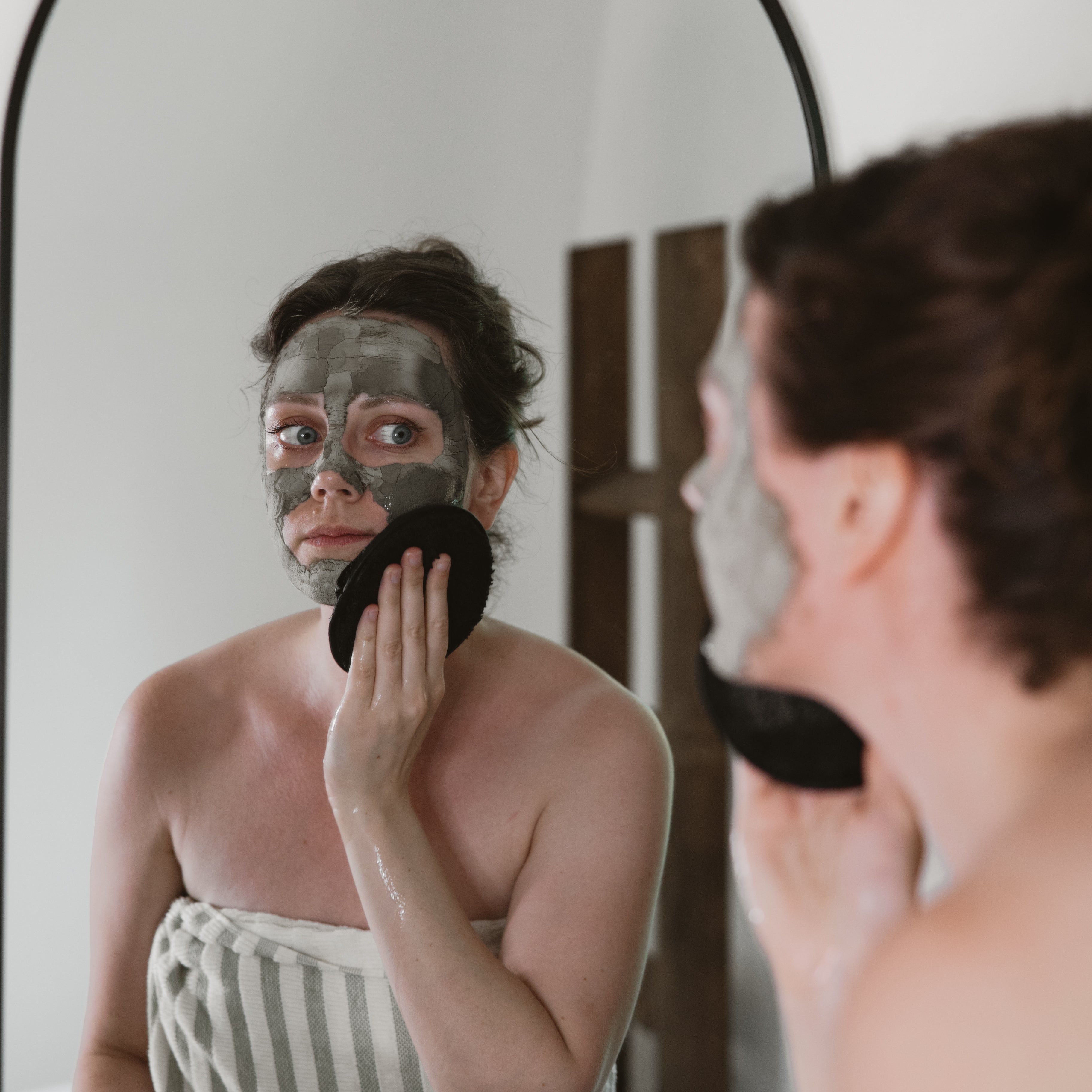 Person applying a face mask in front of a mirror