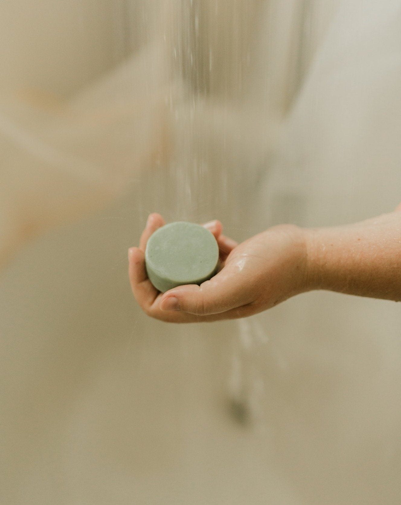 Hand holding a bar of soap under running water