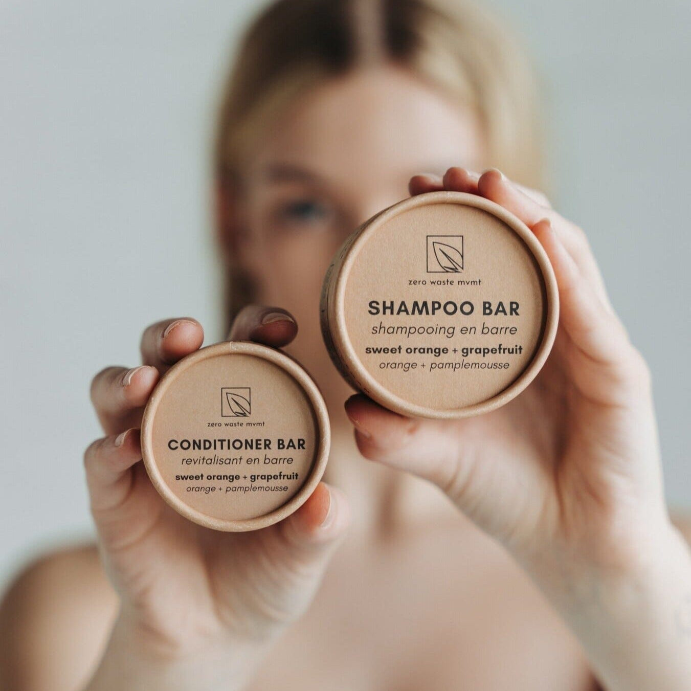 Person holding two shampoo bars with visible branding against a neutral background