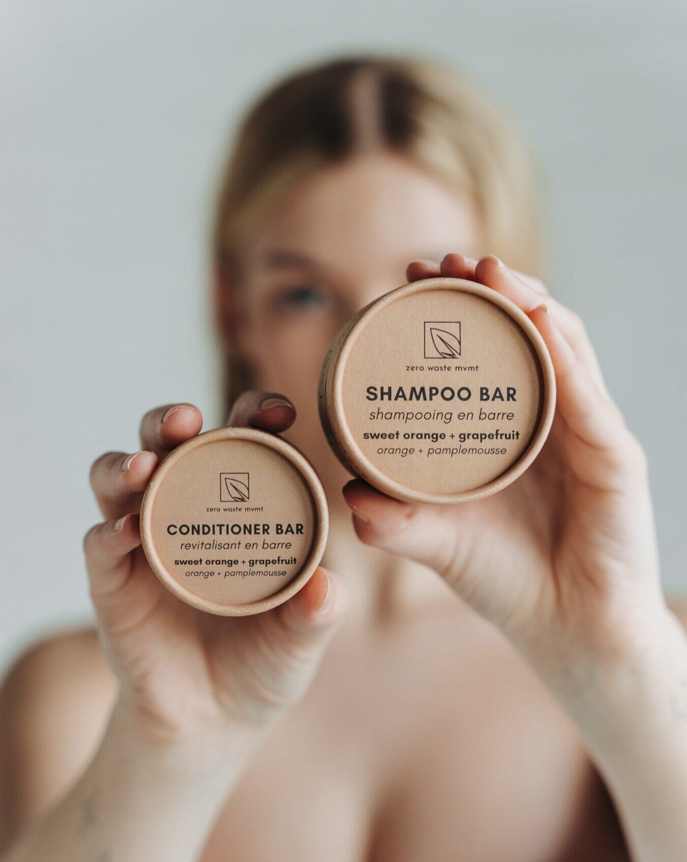 Person holding two shampoo bars with visible branding against a neutral background