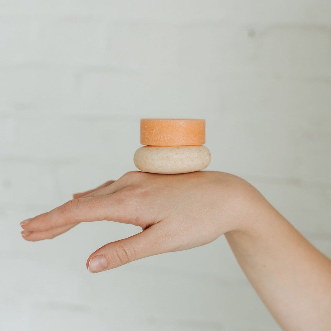 Hand balancing two small ceramic bowls on a plain background