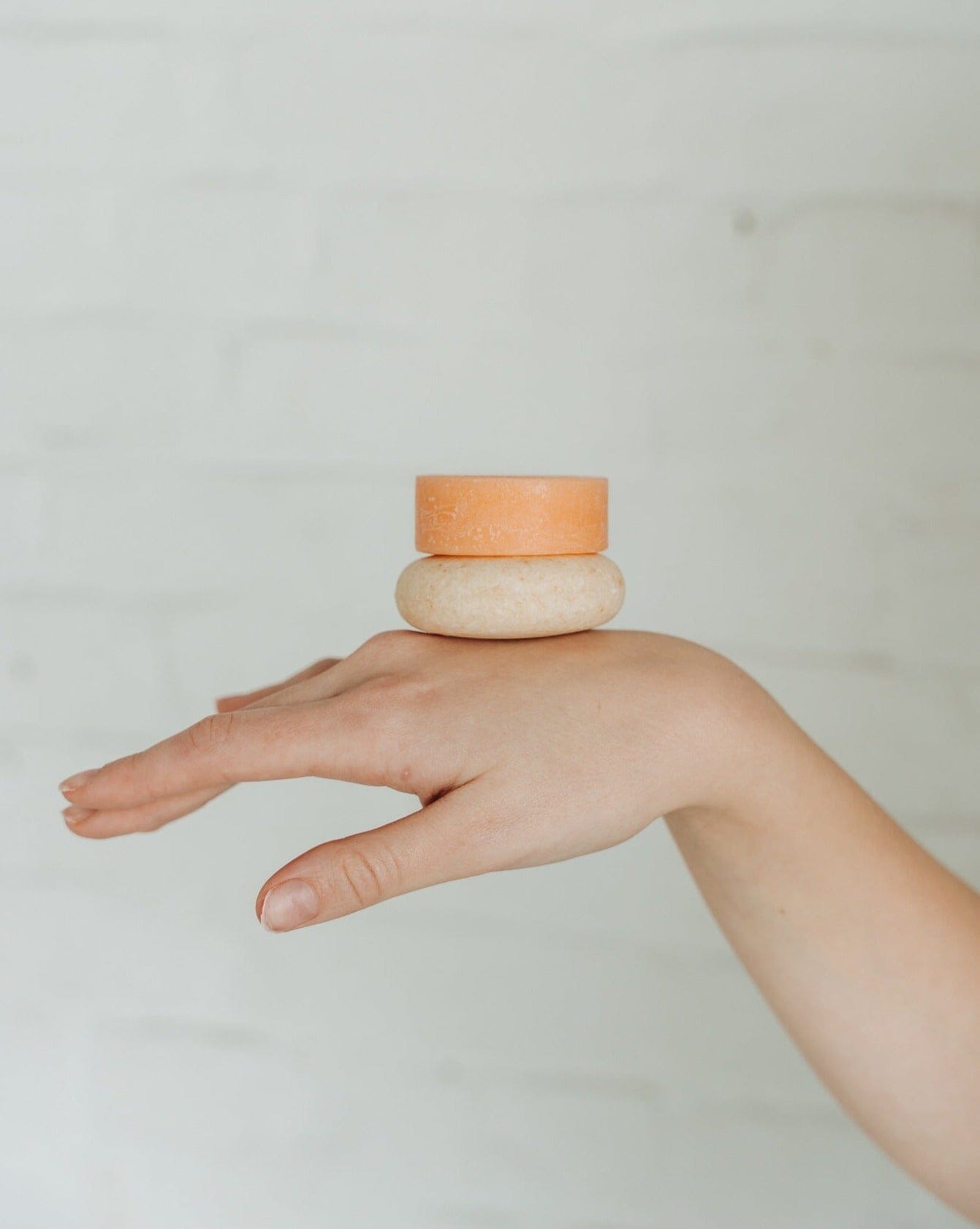 Hand balancing two small ceramic bowls on a plain background