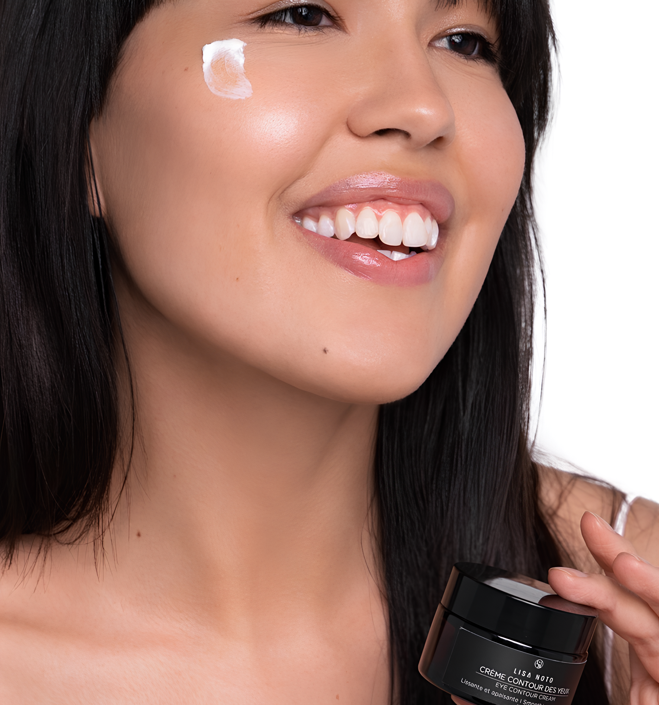 Close-up of a smiling woman with white cream on her cheek, holding a black jar of Lisa Noto eye contour cream 