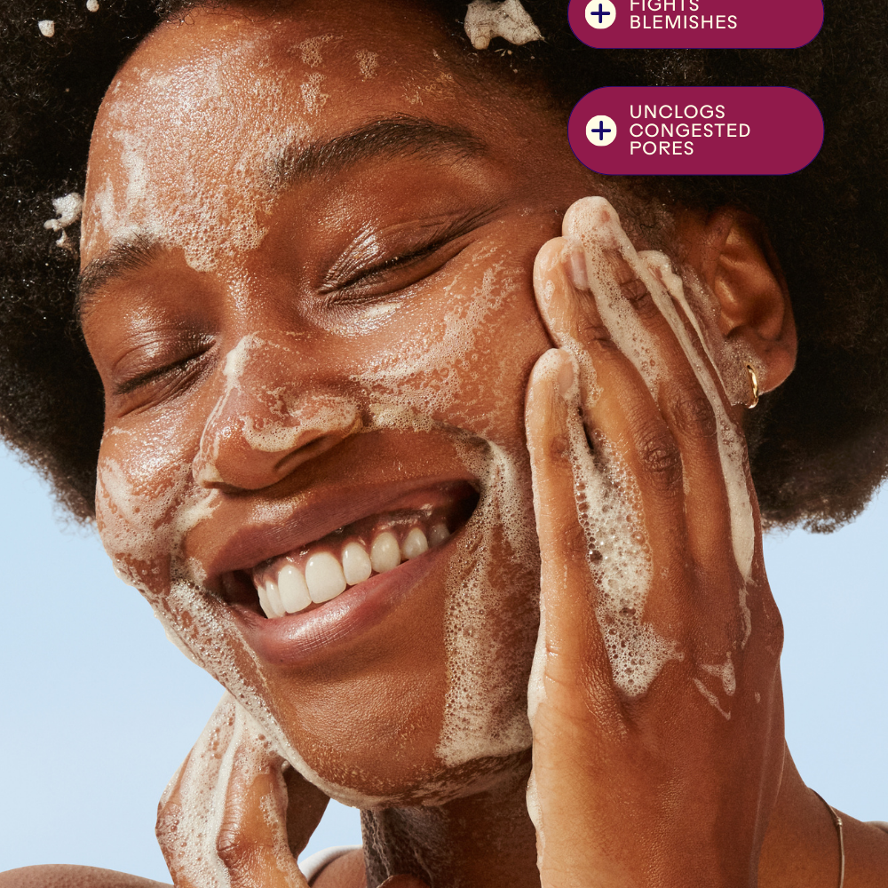 Woman enjoying a foaming cleanser, highlighting benefits of fighting blemishes and unclogging pores.