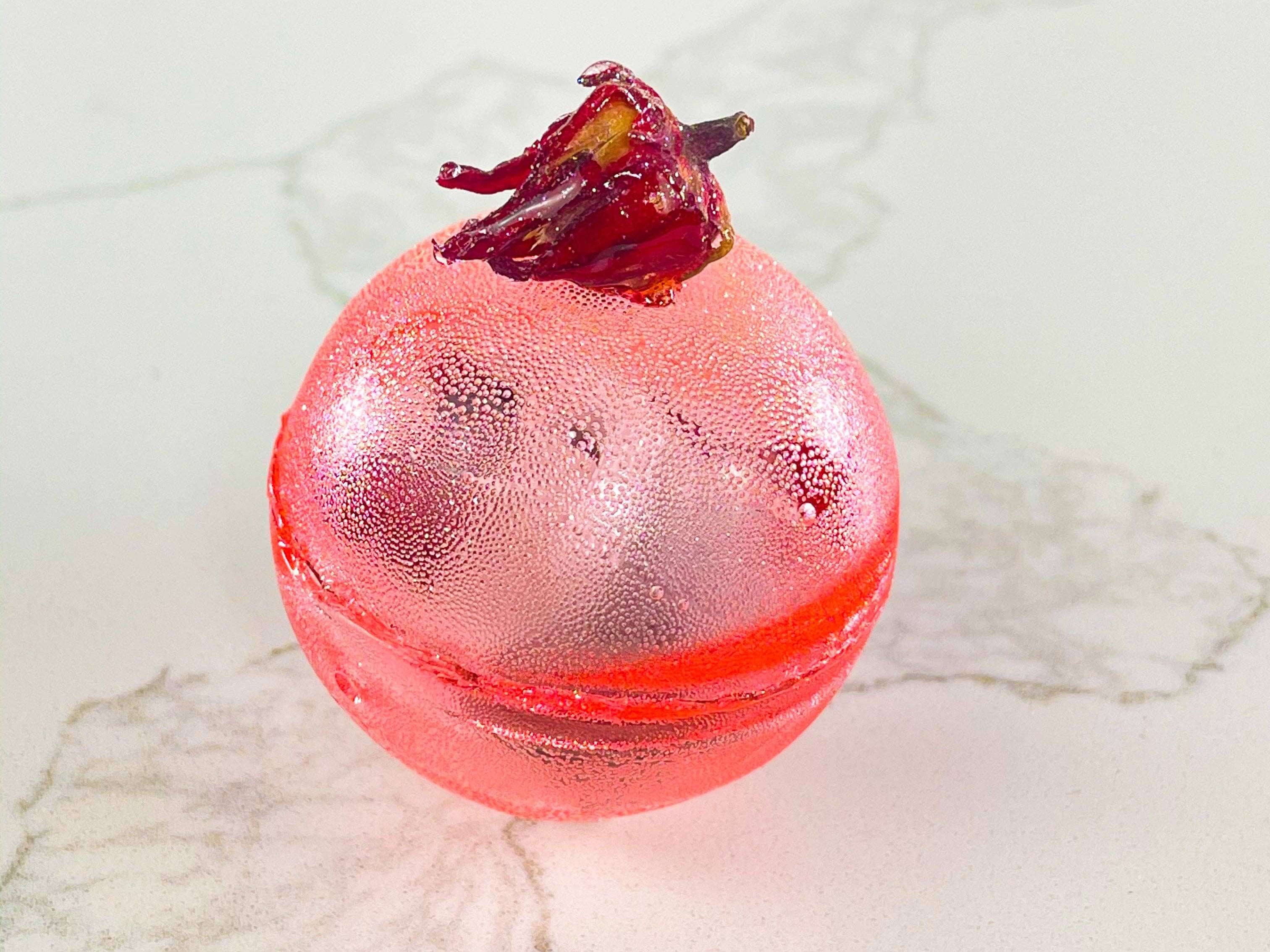 Berry Hibiscus Tea Bomb in a decorative sugar shell with dried hibiscus petals, perfect for gifts and parties.