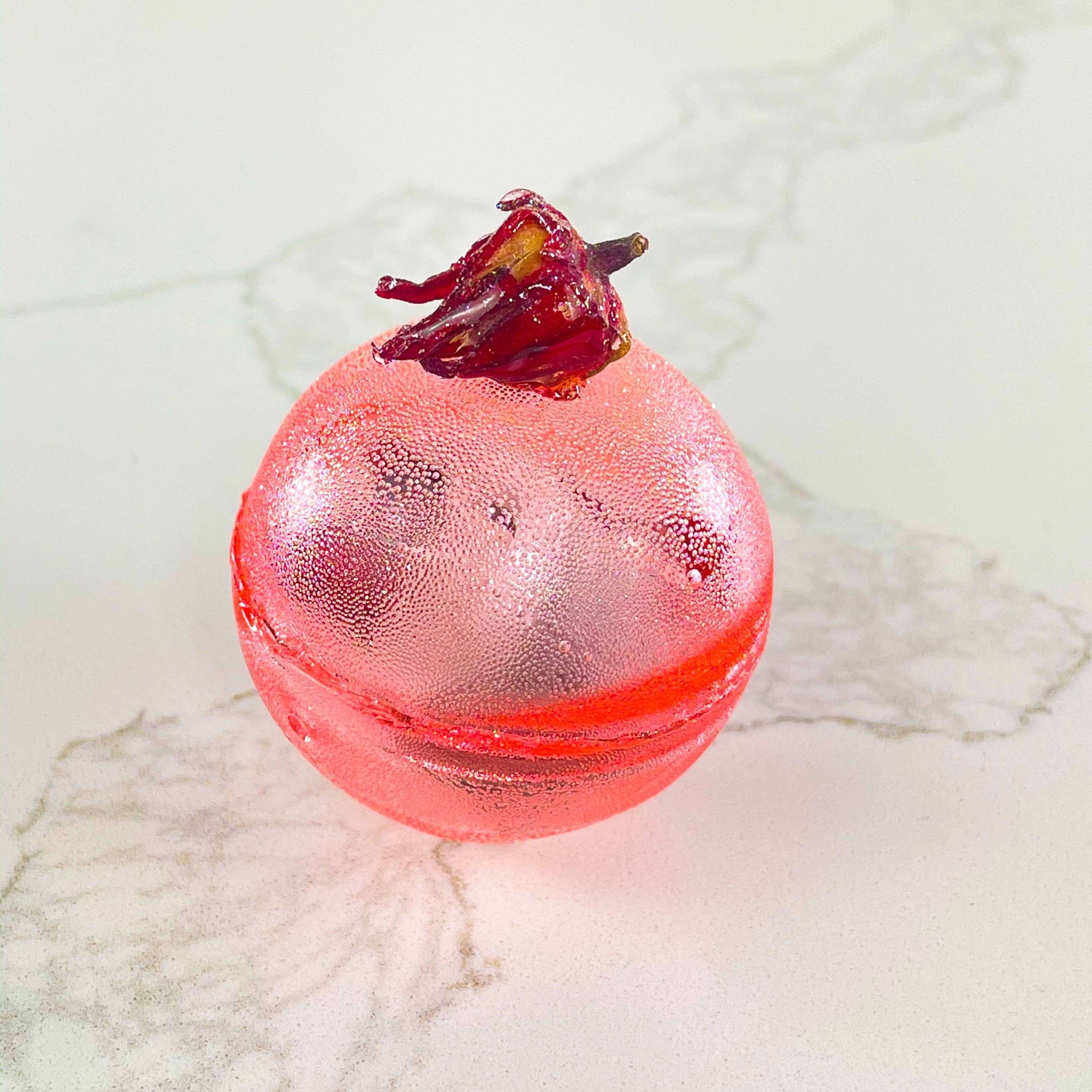 Berry Hibiscus Tea Bomb in a decorative sugar shell with dried hibiscus petals, perfect for gifts and parties.