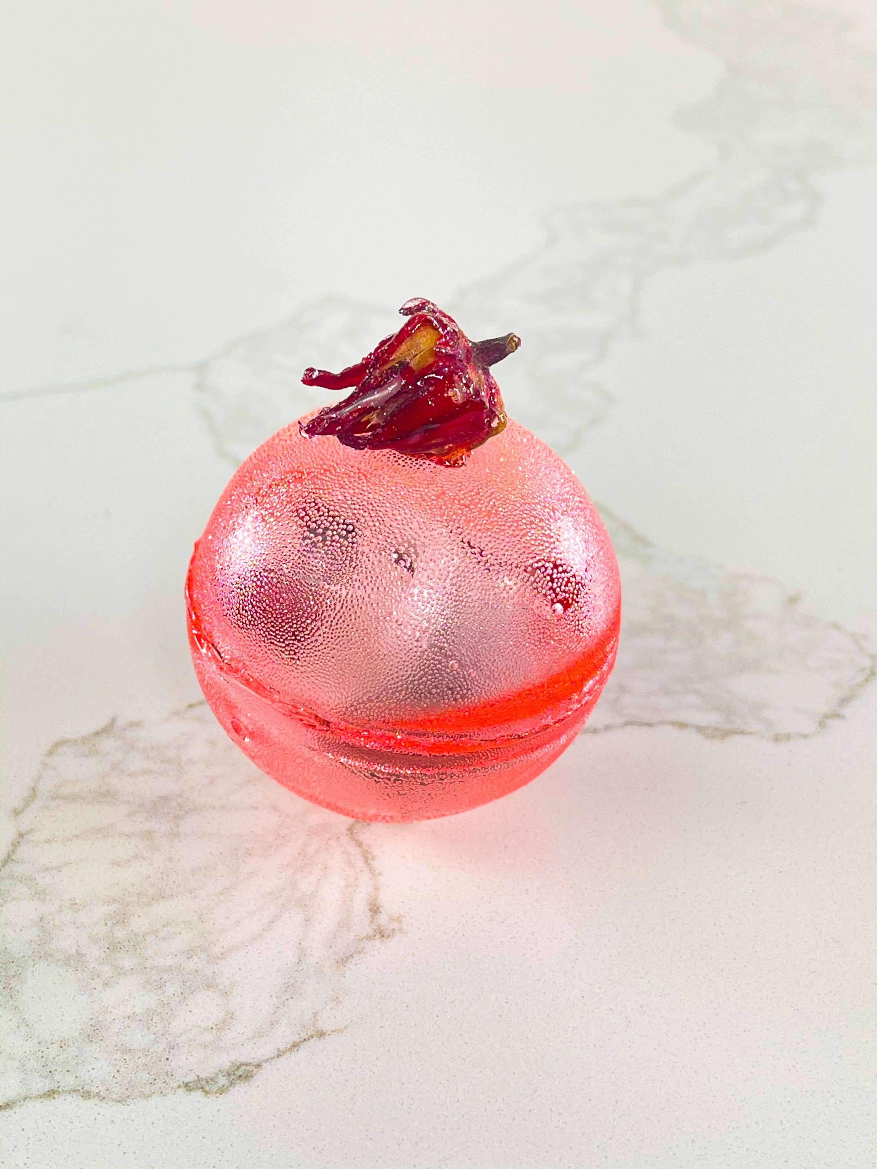 Berry Hibiscus Tea Bomb in a decorative sugar shell with dried hibiscus petals, perfect for gifts and parties.