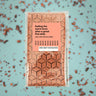 Chocolate bar with a pink label on a blue background with chocolate pieces.