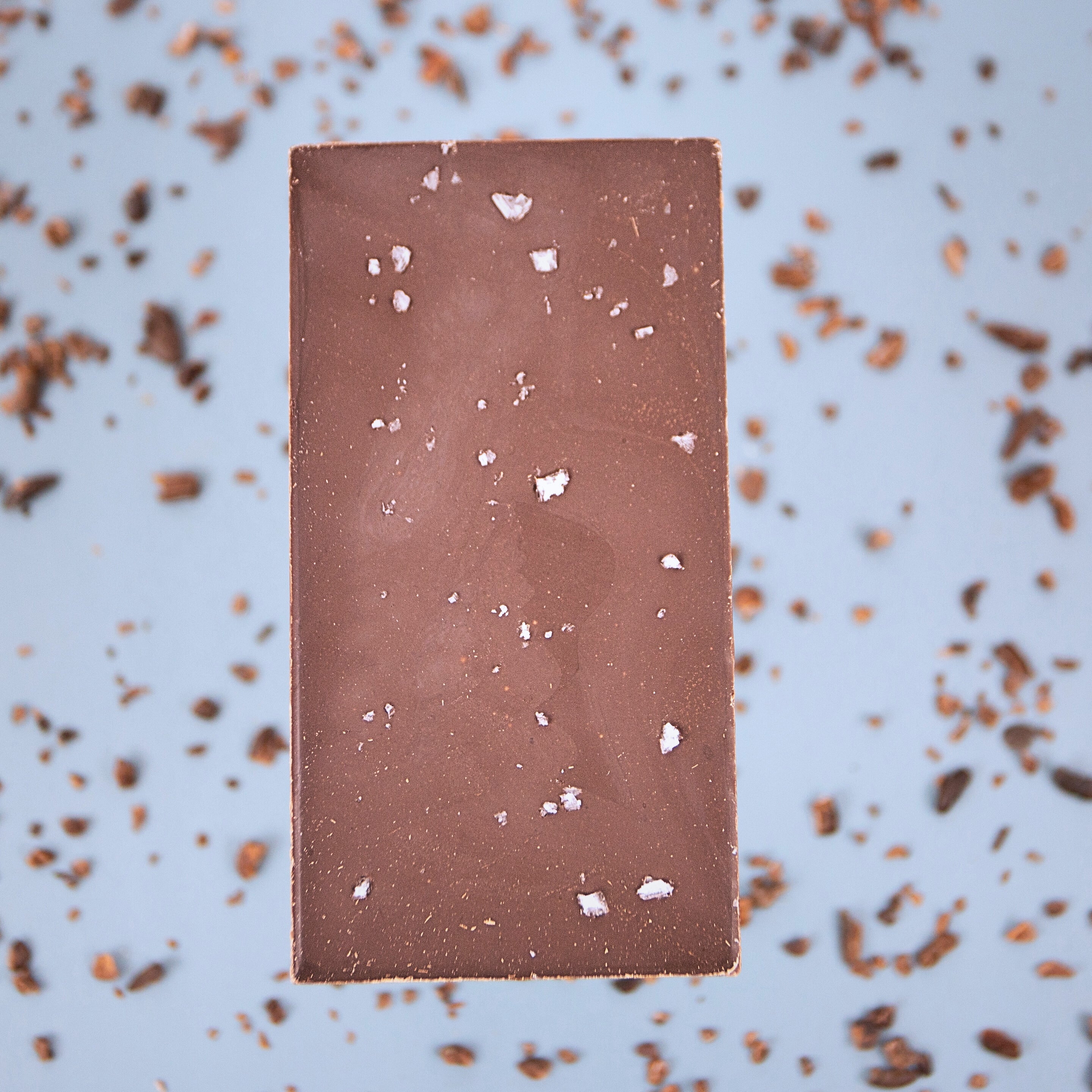 Chocolate bar with cocoa powder on a light blue background