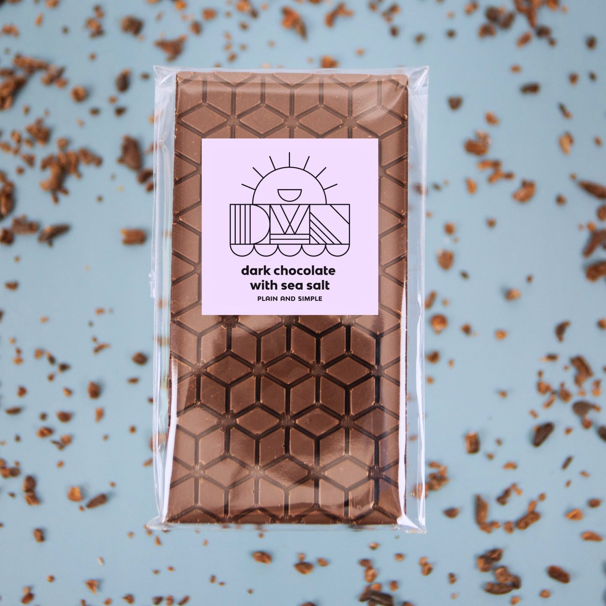 Packaged dark chocolate bar with sea salt on a light blue background