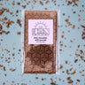 Packaged dark chocolate bar with sea salt on a light blue background