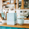 8oz Cool Cyan Glass Travel Tumbler from SOL Cups on kitchen counter with packaging, designed for sustainability and style.