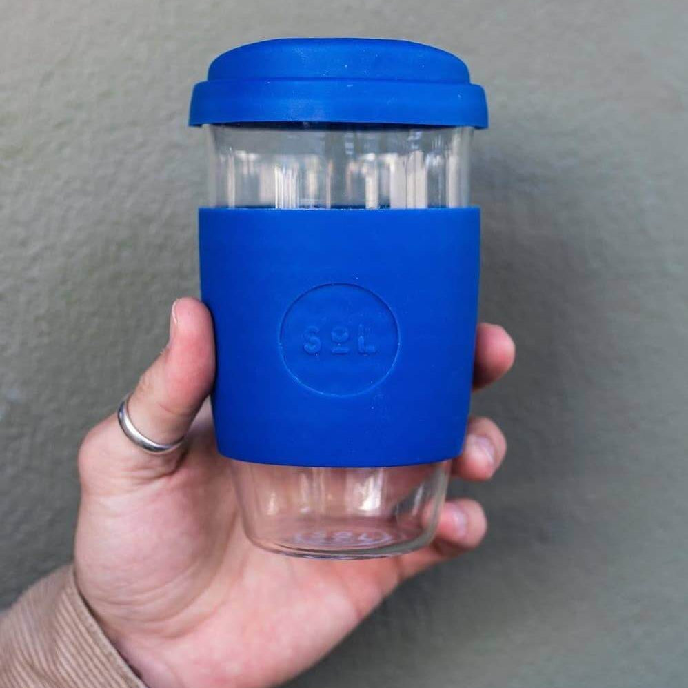 Hand holding a 16oz Winter Bondi Blue glass tumbler with silicone sleeve from SOL Cups.