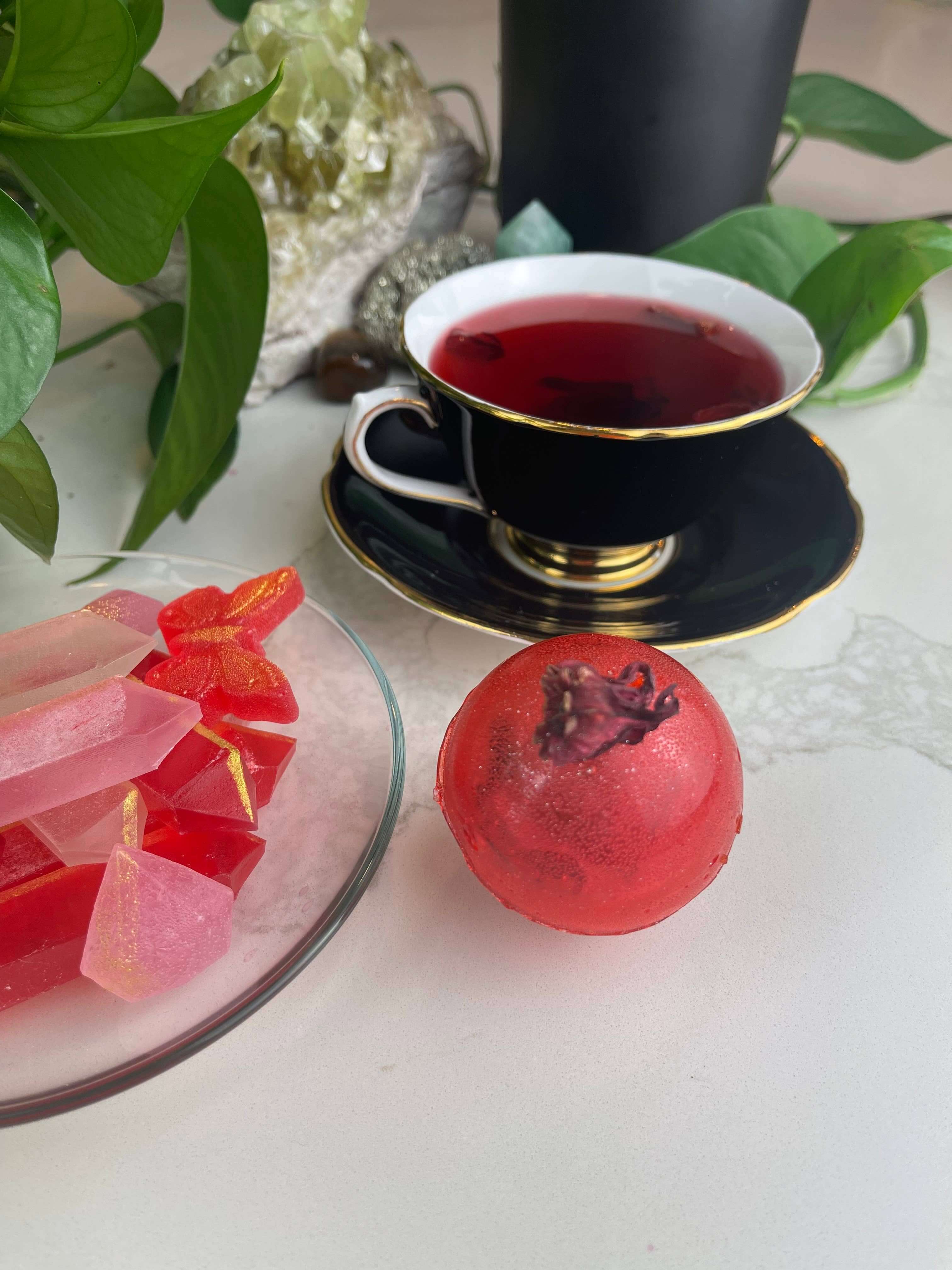 Berry Hibiscus Tea Bomb with a cup of tea and colorful treats, perfect for gifts and party favours.