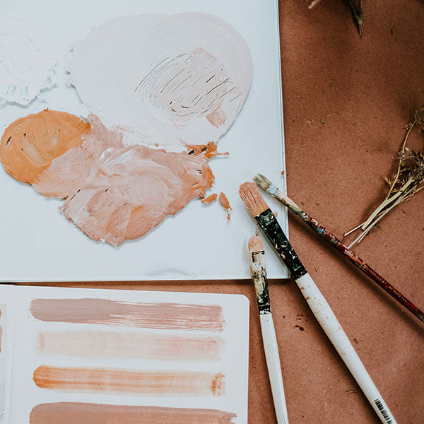 Artistic paint swatches on a canvas with brushes