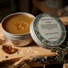 Balm salve in a metal tin with a label on a wooden surface with pine needles and resin.