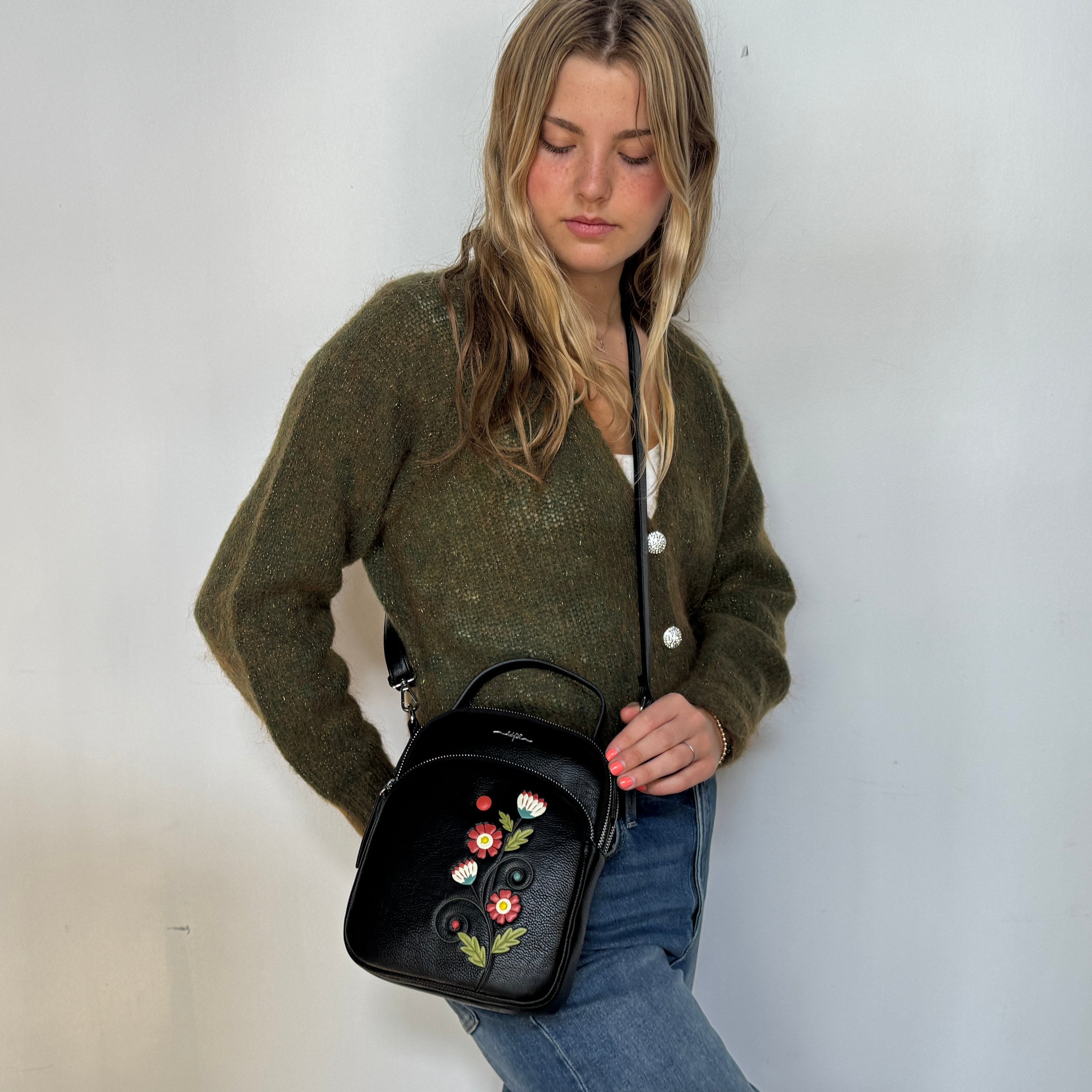 Woman holding a black handbag with floral embroidery against a white background Espe Vegan Corp