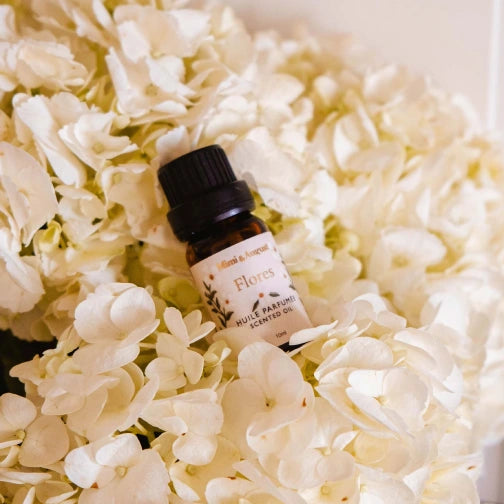 Mimi & August Flores fragrance oil bottle scented Scented oil for diffuser with mint and white musk jasmine and lily on a bed of white flowers